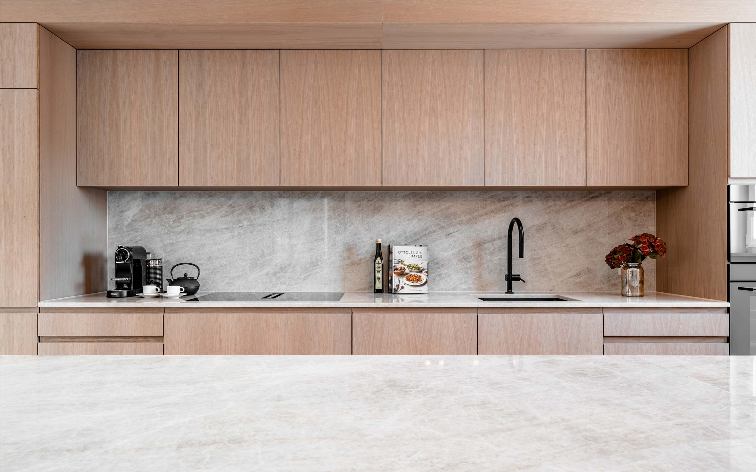Eigentumswohnung. Ansicht Schreinerküche aus Eiche und Marmor. ASA Andermatt Swiss Alps - MACH Architektur.